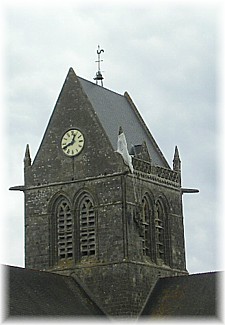 De kerktoren van Sainte-Mère-Eglise, waar de onfortuinlijke sdt Steele, twee uur met zijn parachute is blijven hangen.